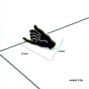 Close-up of Shaka gesture enamel pin showing dimensions 2.7cm by 1.8cm and 3.5g weight