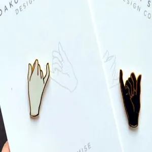 Close-up of black and white enamel pinky promise hand gesture pins on backing card