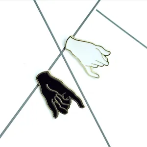 Detail of artistic black and white enamel pinky promise pins with gold metal trim