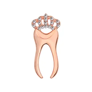 Detailed close-up of a rose gold tooth-shaped brooch featuring a crystal-studded crown