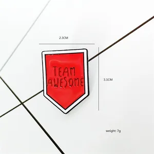 Spilla smaltata Team Awesome rossa a forma di scudo per giacche, 2,3x3,1 cm