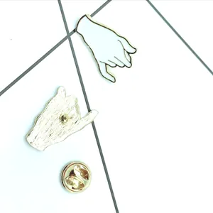 Detail showing the front and back of a gold and white enamel pinky swear gesture brooch
