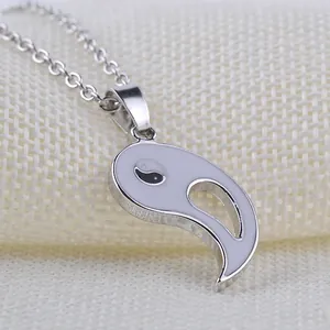 Close-up of yin yang half pendant in silver metal with white enamel on woven fabric