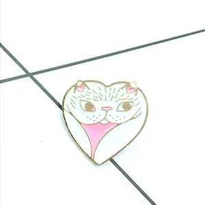 Detail van een hartvormige katten-emaille speld met gouden montuur en roze accenten