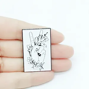Retro black and white enamel brooch featuring a hand with floral vines in a V-sign gesture