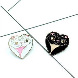 Passende hartvormige katten-emaille pins in zwart en wit met goudkleurige metalen randen