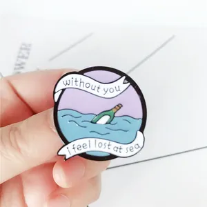 Enamel pin detail showing drifting bottle and sea waves with emotional text engraving