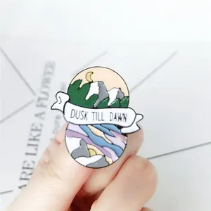 Detail view of the Dusk Till Dawn enamel brooch showing mountain landscape and metal finish
