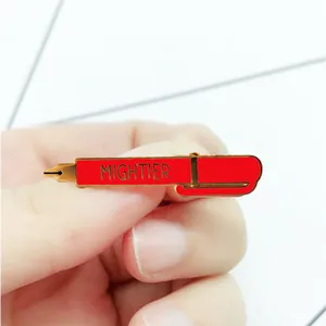Macro shot of red enamel fountain pen brooch with golden trim and MIGHTIER text
