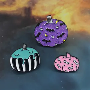 Detailed view of Halloween pumpkin enamel pins with bat, bone, and glitter details