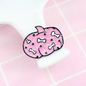 Detail of pink enamel shark brooch with glitter finish and bone patterns for Halloween