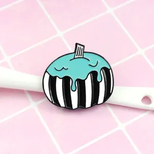 Detailed view of Halloween pumpkin enamel pin with black and white stripes on pink backdrop