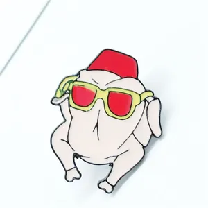 Detailed view of enamel roast turkey pin with red fez and yellow sunglasses detail