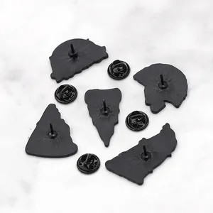 Broches squelette punk noir mat avec fermoirs papillon sur fond de marbre