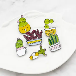 Détail de six broches émaillées en forme de succulentes dans un plat décoratif blanc