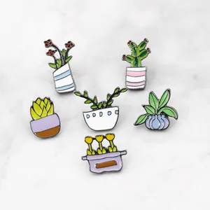 Detailed close-up of six enamel plant and cactus succulent pins on marble surface
