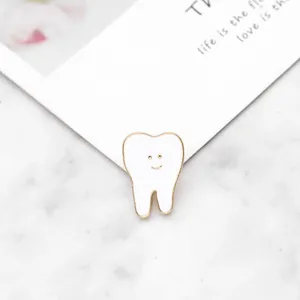 Gros plan d'une jolie broche dent en émail avec visage souriant sur marbre