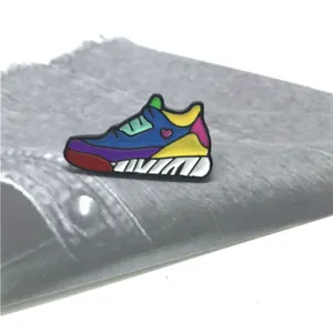 Makroaufnahme der bunten Sneaker-Emaille-Anstecknadel mit Herz auf grauem Denim-Stoff