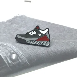 Makro-Detail einer Emaille-Sneaker-Brosche mit Herzdesign auf grauem Denim-Stoff