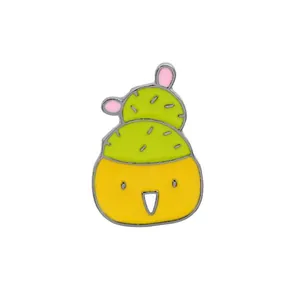 Détail d'une broche en émail représentant un corps jaune et un chapeau de cactus vert