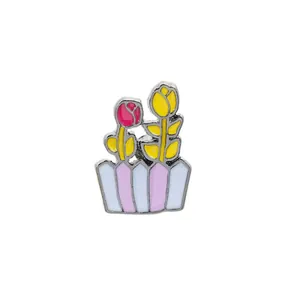 Détail de la broche émaillée avec des tulipes roses et jaunes dans un pot à rayures