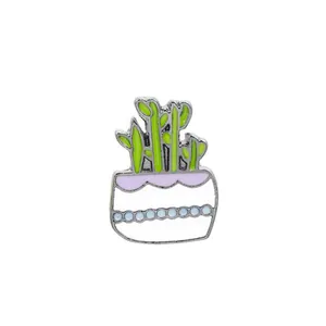 Détail d'une broche en émail mignonne avec plante verte et pot blanc à pois bleus