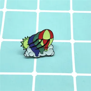 Detail of colorful hot air balloon enamel pin with cloud and sun elements