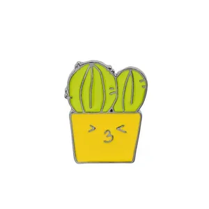 Détail d'un pin's en émail cactus mignon dans un pot jaune avec un visage souriant