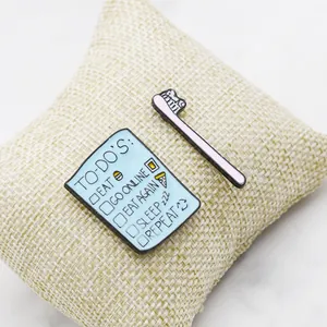 Cute cat-themed enamel pins featuring a to-do list and a cat toothbrush design