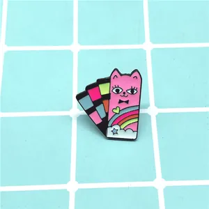 Detail of pink enamel cat brooch with rainbow and color palette on blue checkered background