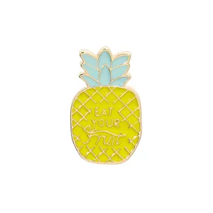 Detail of pineapple enamel pin with Eat Your Fruit slogan and gold metal grid pattern