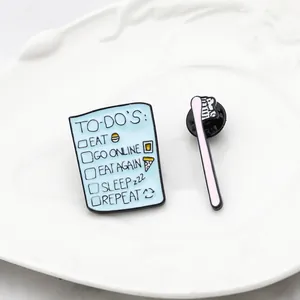 Detailed close-up of enamel pins featuring a blue to-do list and a pink toothbrush design