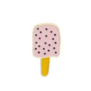 Detail view of a pink ice cream enamel pin with gold plating and fruit-inspired dots