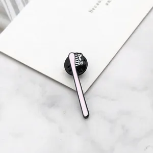 Detail shot of a minimalist pink toothbrush enamel lapel pin on a marble texture