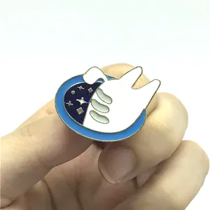 Dettaglio di una mano che regge una spilla smaltata con motivo luna stellata