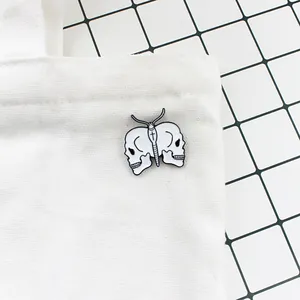 Detail of gothic white skull butterfly enamel pin attached to a white canvas bag