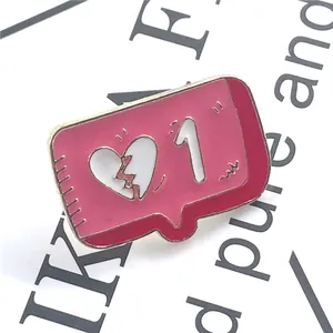 Macro shot of pink enamel message bubble pin with broken heart and gold metallic edges