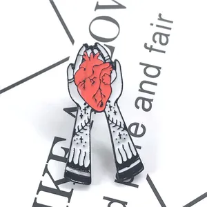 Détail d'un pin's en émail avec cœur anatomique et mains aux motifs d'étoiles