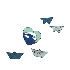 Détail de broches en émail avec avions en papier, bateaux et motif de vague en cœur