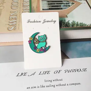 Détail d'une broche chat sur lune en émail vert menthe fixée sur une carte