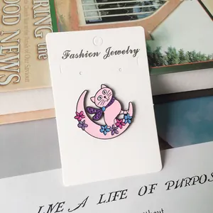 Détail de la broche en émail coloré avec chat et lune sur carte de présentation