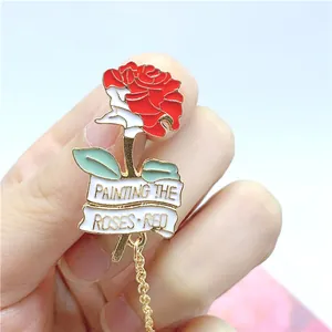 Detail of red rose enamel brooch with Painting the Roses Red scroll and gold chain