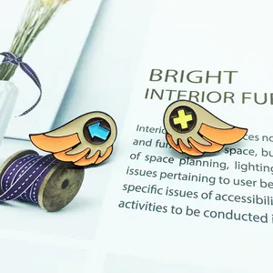 Close-up of cute cartoon wing-shaped enamel pins with colorful symbols on a stylish background