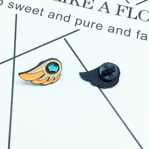 Detailed view showing front and back of cartoon wing enamel pins with blue arrow detail