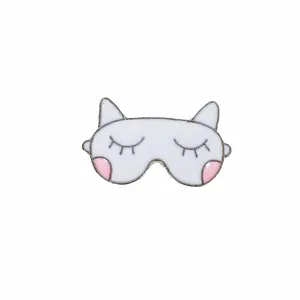 Dettaglio della spilla in smalto bianco a forma di maschera da gatto su fondo bianco