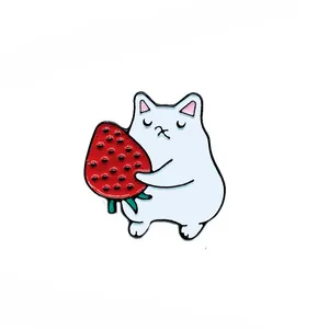Détail du pin's chat blanc en émail tenant une fraise avec des bords en métal poli