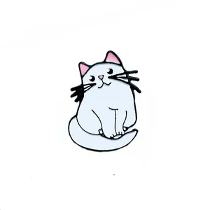 Détail d'un pin's en émail de chat blanc mignon avec oreilles roses sur fond blanc pur