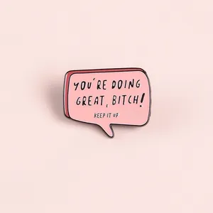 Dettaglio della spilla in smalto rosa con frase motivazionale per accessori denim