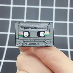 Close-up of retro cassette enamel pin featuring Sad Songs text on checkered background
