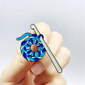 Detailed view of a creative blue crochet ball brooch featuring a metal knitting needle